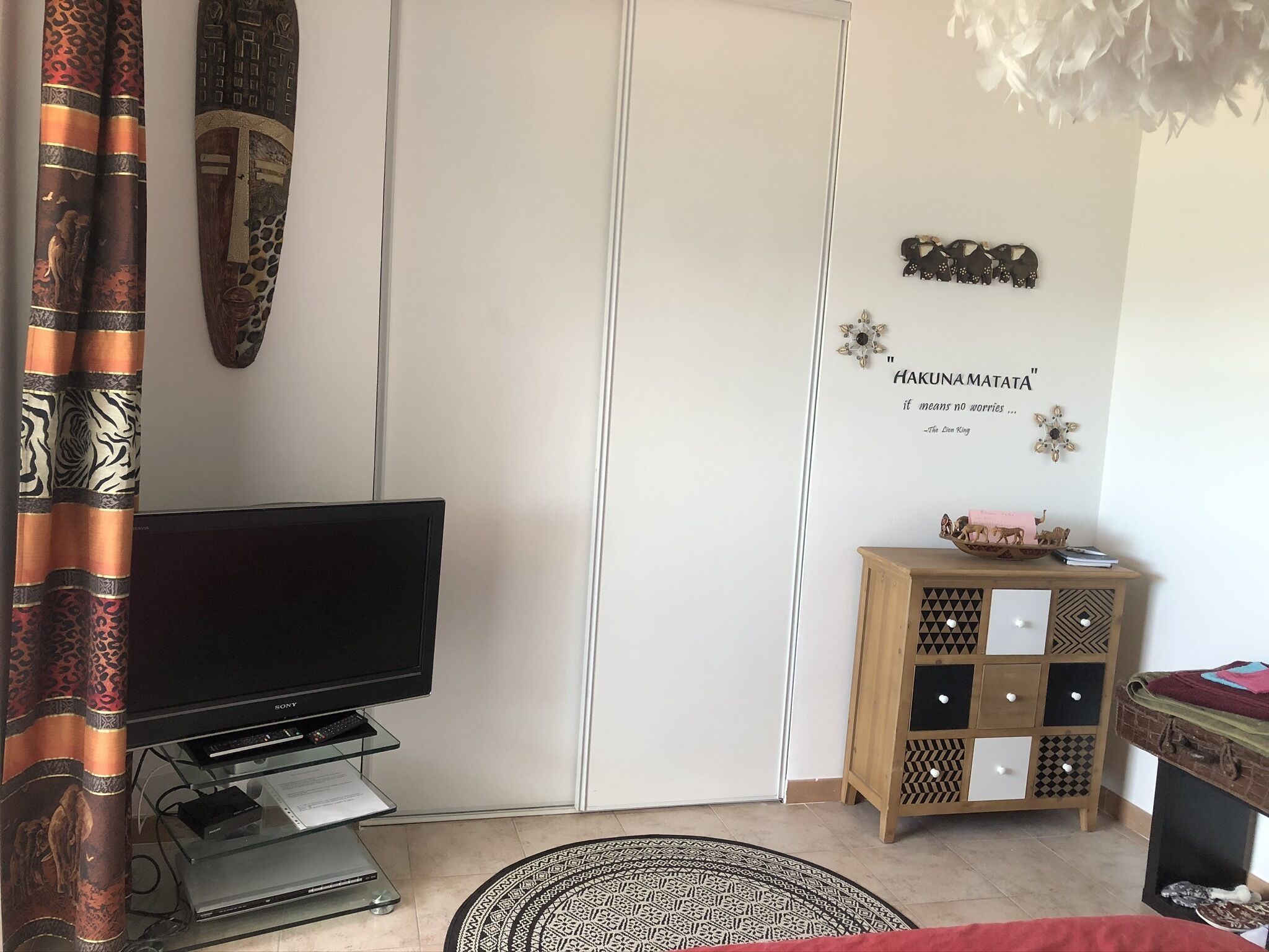 A living room with a flat-screen TV, a cabinet with decorative items, and a quote on the wall.