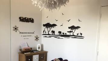 A room with a bed, a wooden cabinet, a wall decal, and a hanging light fixture.