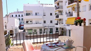 A balcony with a table set for tea, white buildings in the background, and a clear sky. - Oasis Sinia by Hello Homes Sitges (Sitges)