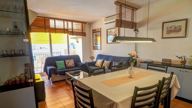 A compact living space with a dining area, a sofa, and a kitchen counter. - Oasis Sinia by Hello Homes Sitges (Sitges)