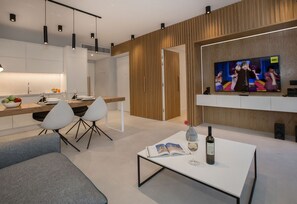 A modern living room with a white coffee table, a sofa, and a dining area with a wooden table and chairs.