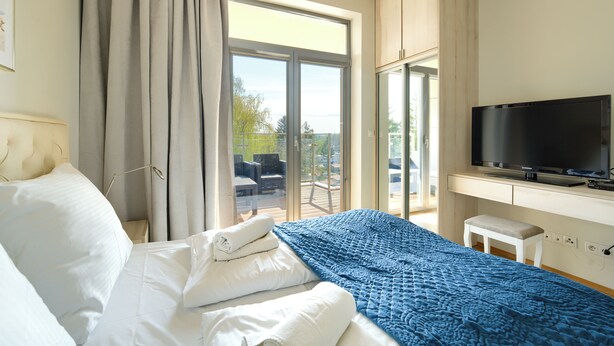 Une chambre d’hôtel avec un lit, une télévision et un balcon aménagé avec du mobilier d’extérieur.