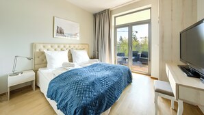Une chambre d’hôtel comprenant un lit, un bureau, une télévision, une table de chevet, une lampe et un balcon aménagé avec du mobilier d’extérieur.