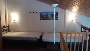 A small, cozy room with two single beds, a wooden ceiling, and a painting on the wall. - 20m from ski slopes, 4th floor, view ski slopes, 42m², La Plagne (La Plagne)