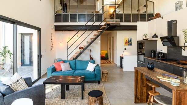 A spacious living area with a sofa, coffee table, and a staircase leading to an upper level. - LOFT VILLAGE HOUSE+AIR CONDITIONING+TERRACE, NEAR THE GOLF COURSE. (Vernègues)