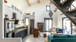 A modern kitchen with a central island, a dining area with a table and chairs, and a living room with a sofa. - LOFT VILLAGE HOUSE+AIR CONDITIONING+TERRACE, NEAR THE GOLF COURSE. (Vernègues)
