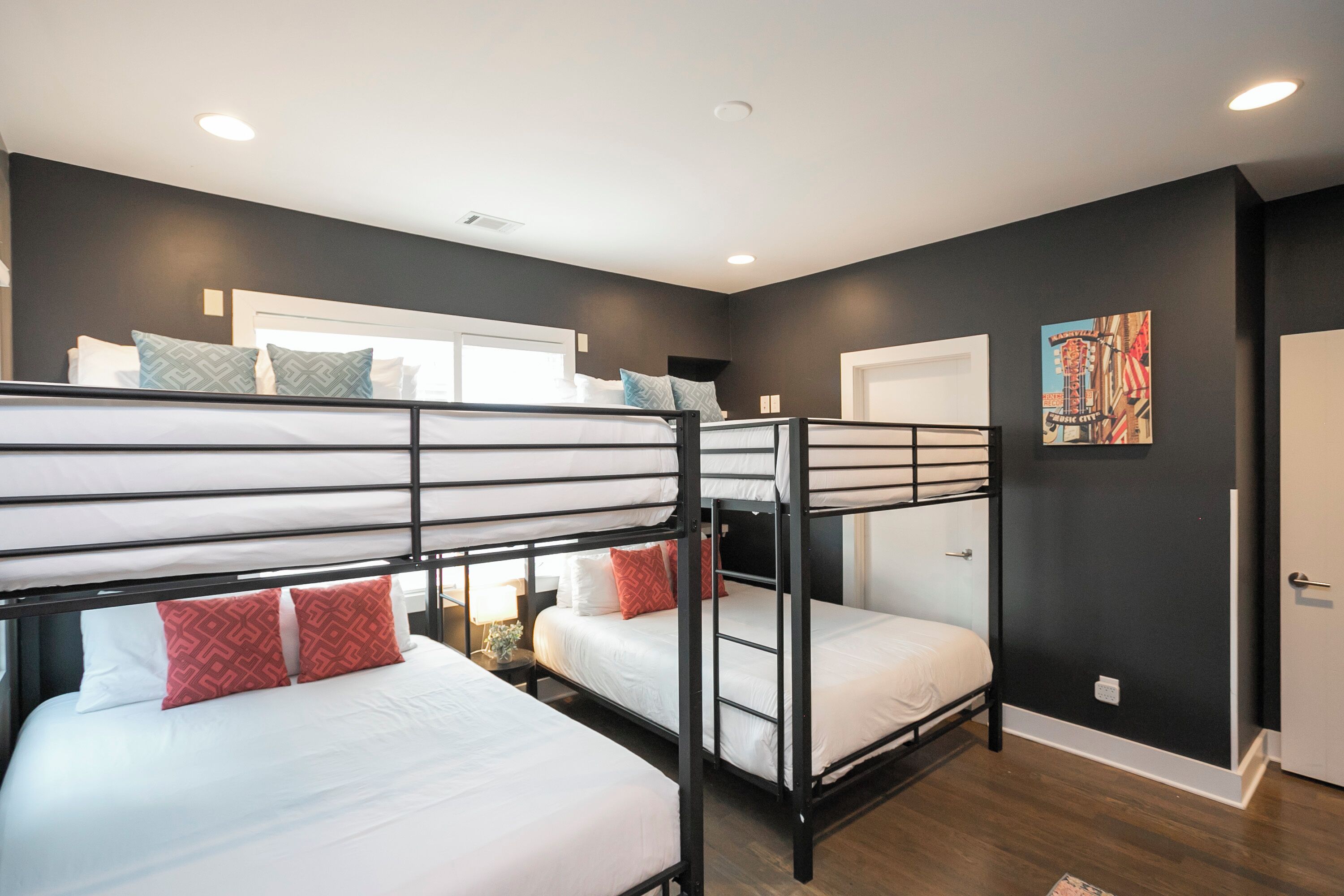 A room with bunk beds, a door, and a wall with a painting.