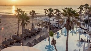 Resort com piscina, espreguiçadeiras e palmeiras.