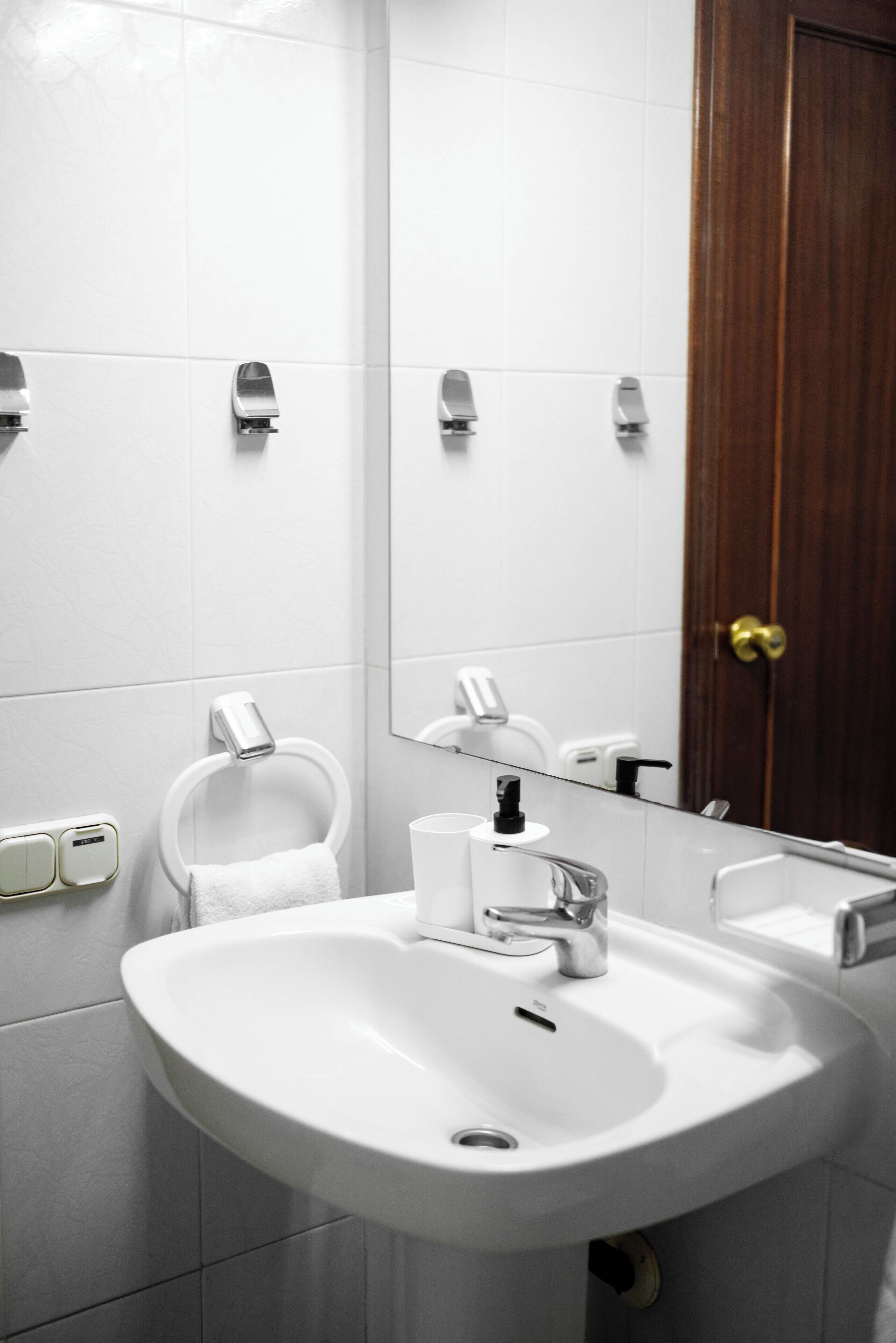A bathroom with a white sink, a mirror, and a wooden door.