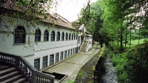 A building with a long corridor, arched windows, and a staircase leading to a covered area. - Alojamento Correia (Amares)