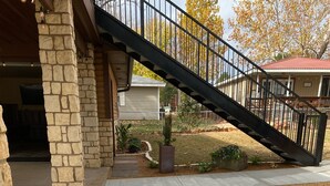 Un edificio de piedra con una escalera negra que conduce a una zona cubierta.
