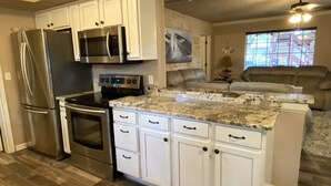 Una cocina moderna con armarios blancos, electrodomésticos de acero inoxidable y encimera de granito.