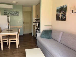 A compact living space with a dining table, a sofa, a kitchen area, and a door leading to another room. - Cap Esterel 2P Sea view 5Pers. Air-conditioned (Saint-Raphaël)