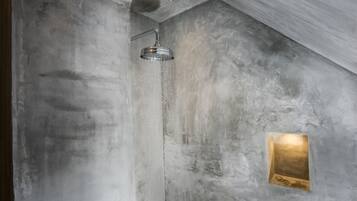 Une douche au design moderne, un mur à texture et un petit panneau lumineux.