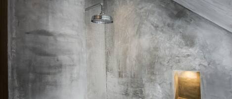 A shower with a modern design, a textured wall, and a small illuminated panel.