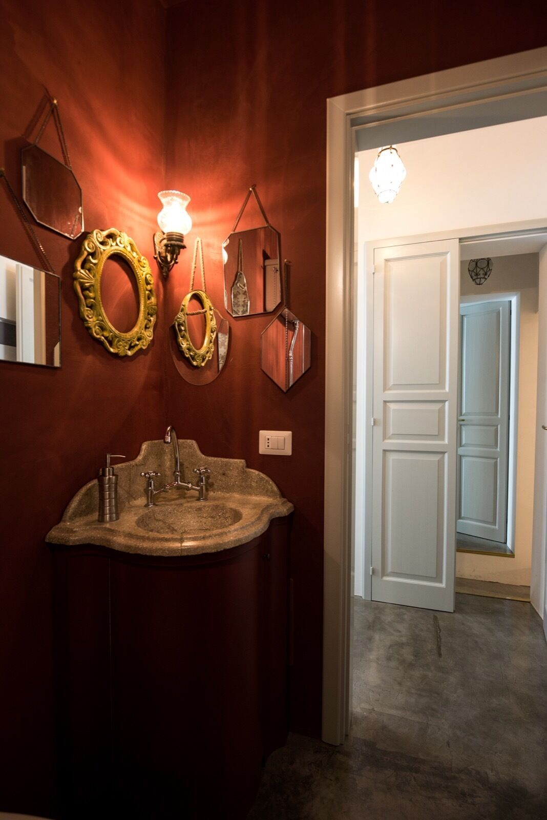A bathroom with a granite sink, a wall-mounted mirror, and a light fixture.