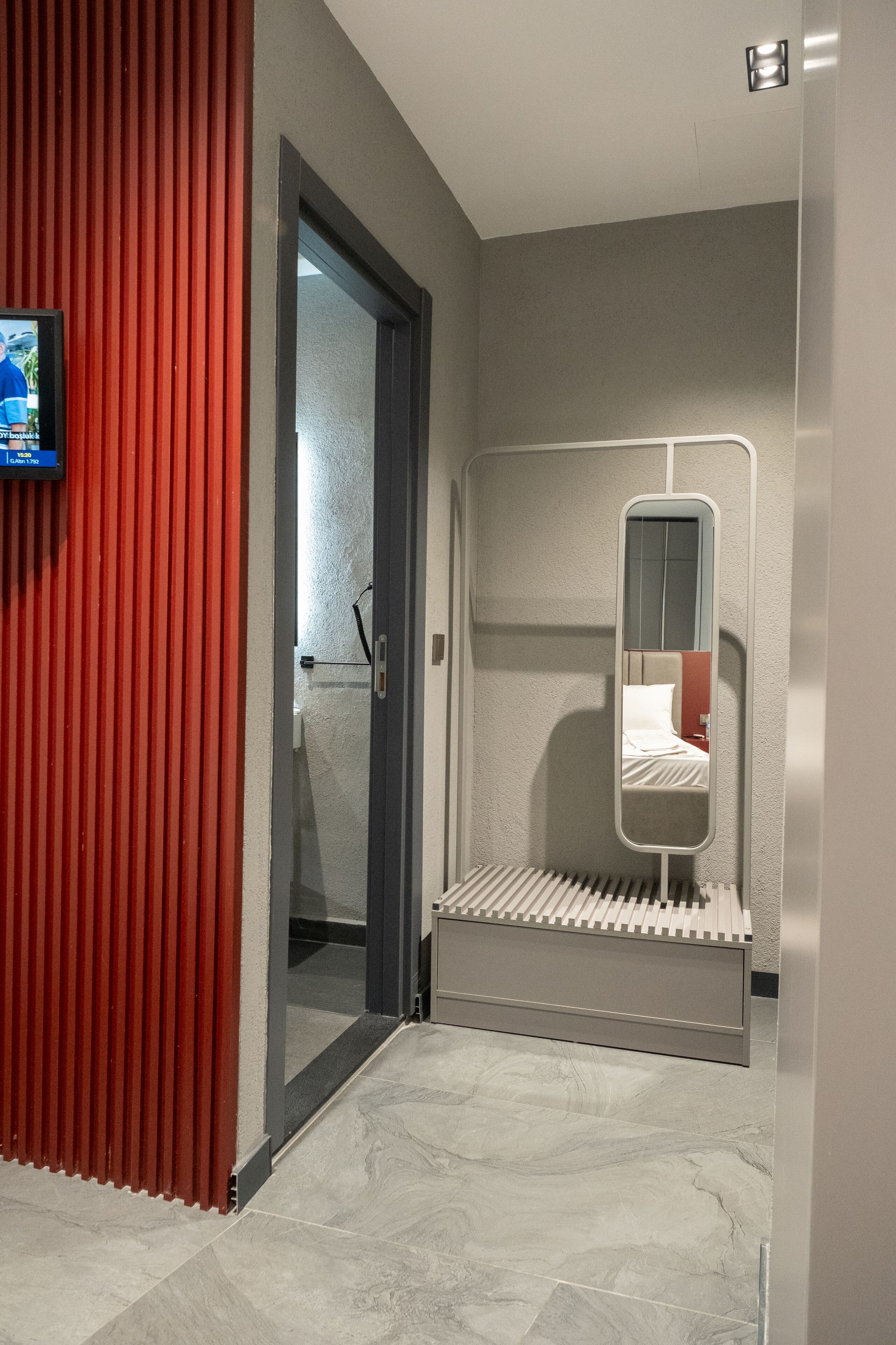 Une salle de bain moderne avec une douche, un miroir et un mur d’accent de couleur rouge.
