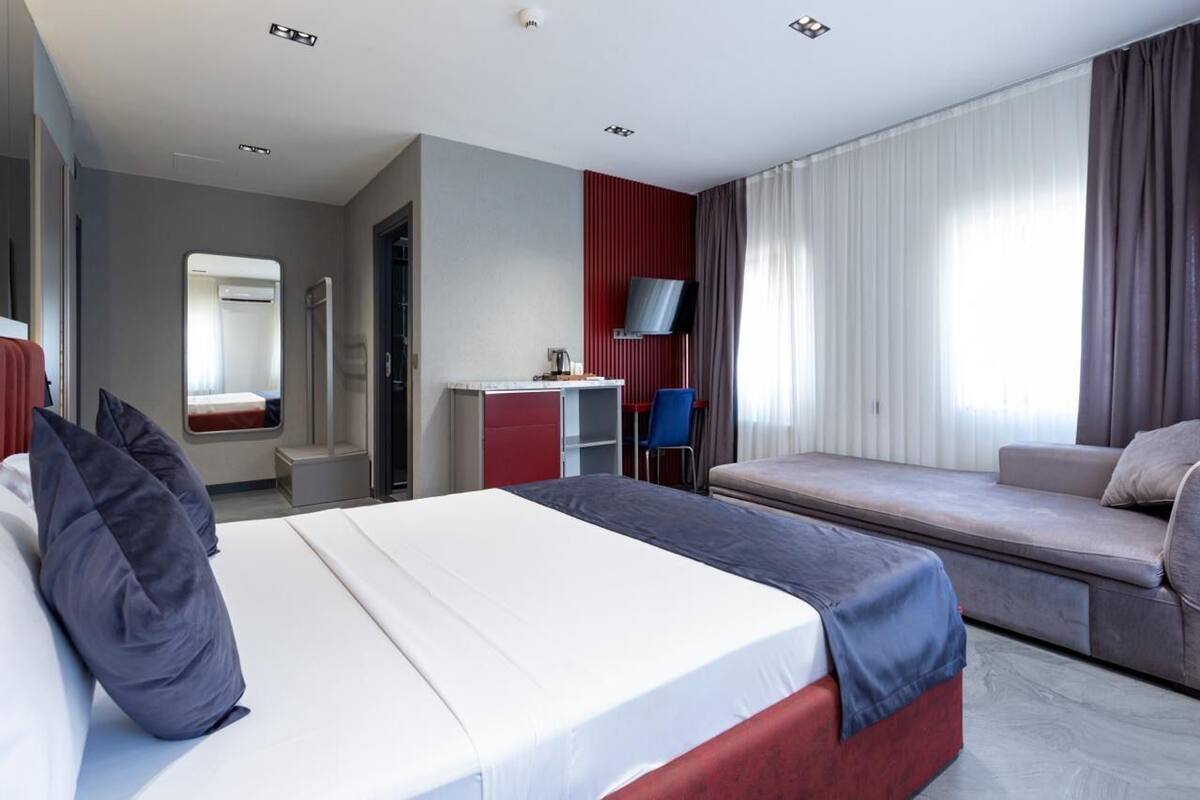 A hotel room with a bed, a desk, a TV, and a sofa.