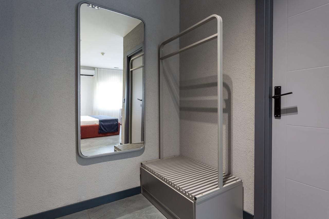 A bathroom with a mirror, a shower enclosure, and a bench.