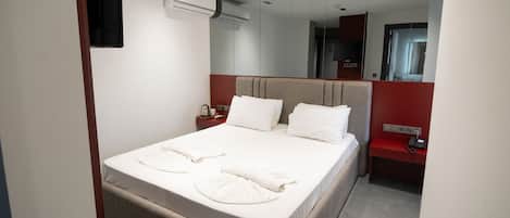 Een hotelkamer met een bed, een nachtkastje, een rode bank en een spiegel.