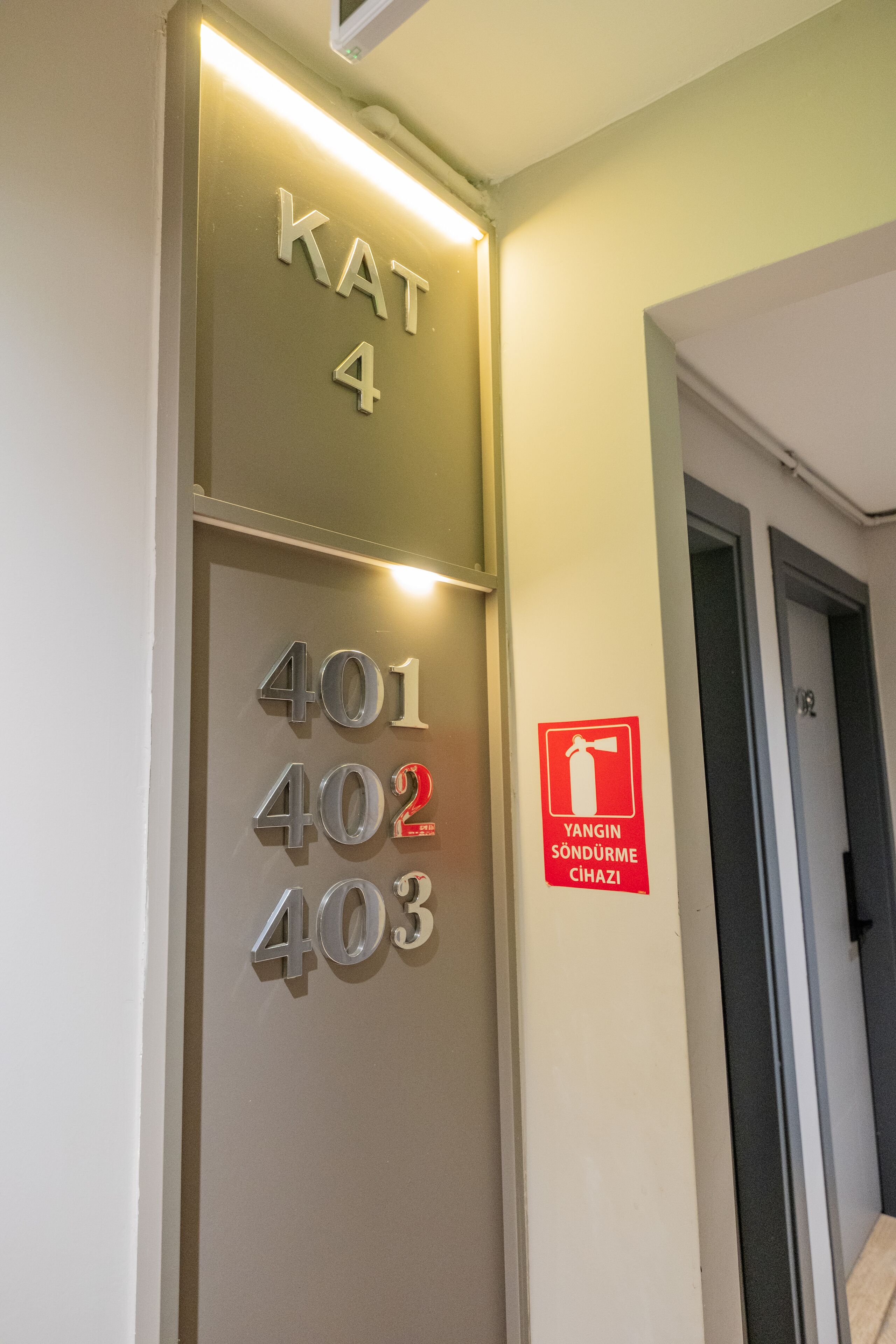 A hotel interior with a wall displaying room numbers 401, 402, 403, and 404, and a fire safety sign.