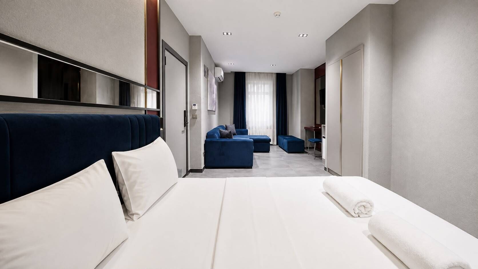 Une chambre d’hôtel dotée d’un grand lit, d’un coin salon avec des canapés, d’un bureau et d’un miroir.