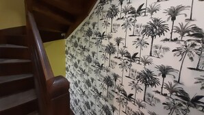 Een trap met een houten leuning en een muur met behang van een tropische palmboom.