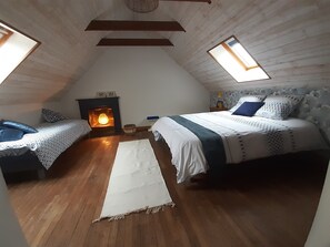 Une chambre confortable située sous les toits, avec deux lits, une cheminée et des fenêtres de toit.