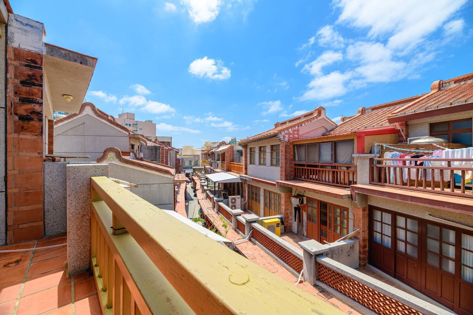 A narrow street with traditional buildings, a visible laundry line, and a clear blue sky.