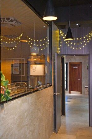 A modern hotel lobby with a reception desk, a wooden door, and string lights.