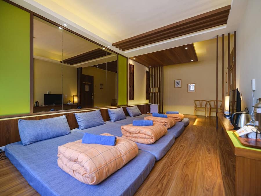 Una habitación de hotel moderna con una cama grande, piso de madera y un espejo amplio.