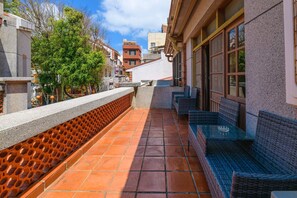 A rooftop terrace with tiled flooring, a stone wall with a geometric pattern, and wicker furniture. - Penghu's Peace - B&B (Magong)