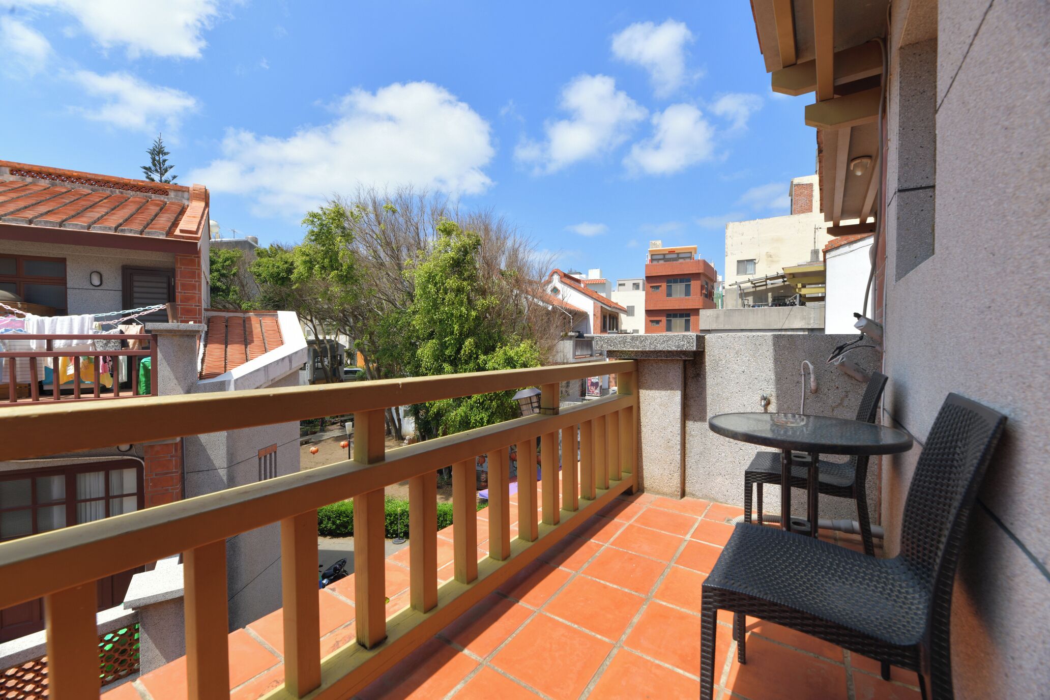 A balcony with a table and chairs, a railing, and a view of neighboring buildings.