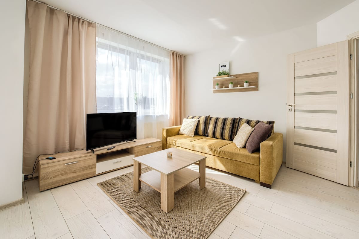 Una sala de estar con un sofá, una mesa de centro, un televisor y un mueble de madera.