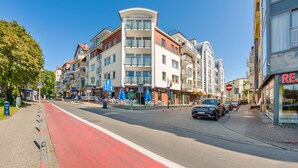 Una calle con edificios de varios pisos, un carril bici rojo y un coche estacionado.
