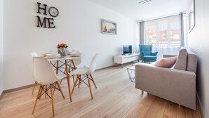 Una sala de estar moderna con comedor, un sofá, un televisor y un cuadro en la pared.