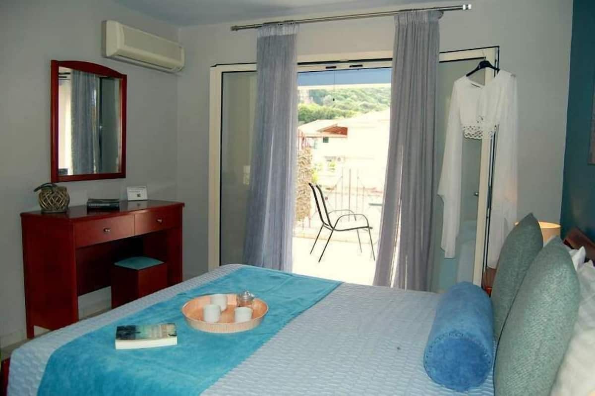 A hotel room with a bed, a desk, a mirror, and a view of the outdoors.