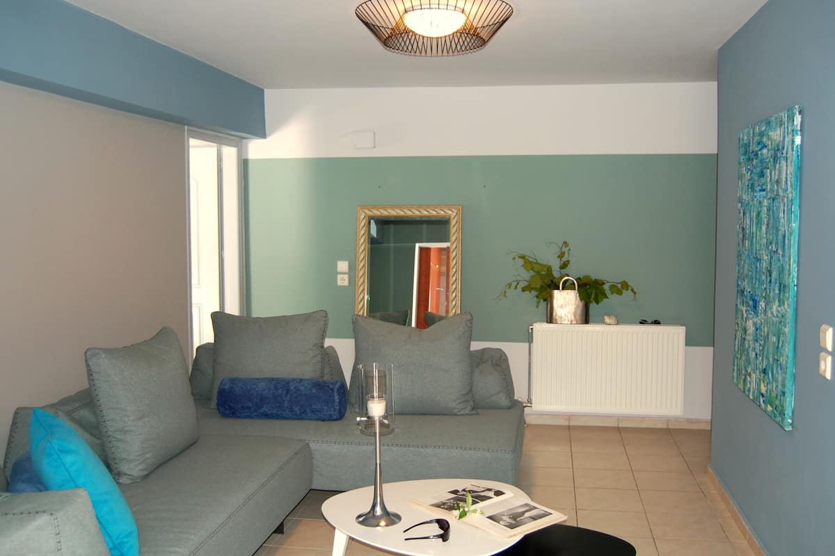A living room with a grey sofa, a small white table, and a mirror on the wall.