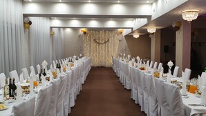 A banquet hall with long tables set for a formal event, featuring white tablecloths, glassware, and neatly arranged food. - Hotel Gniecki (Pruszcz Gdanski)