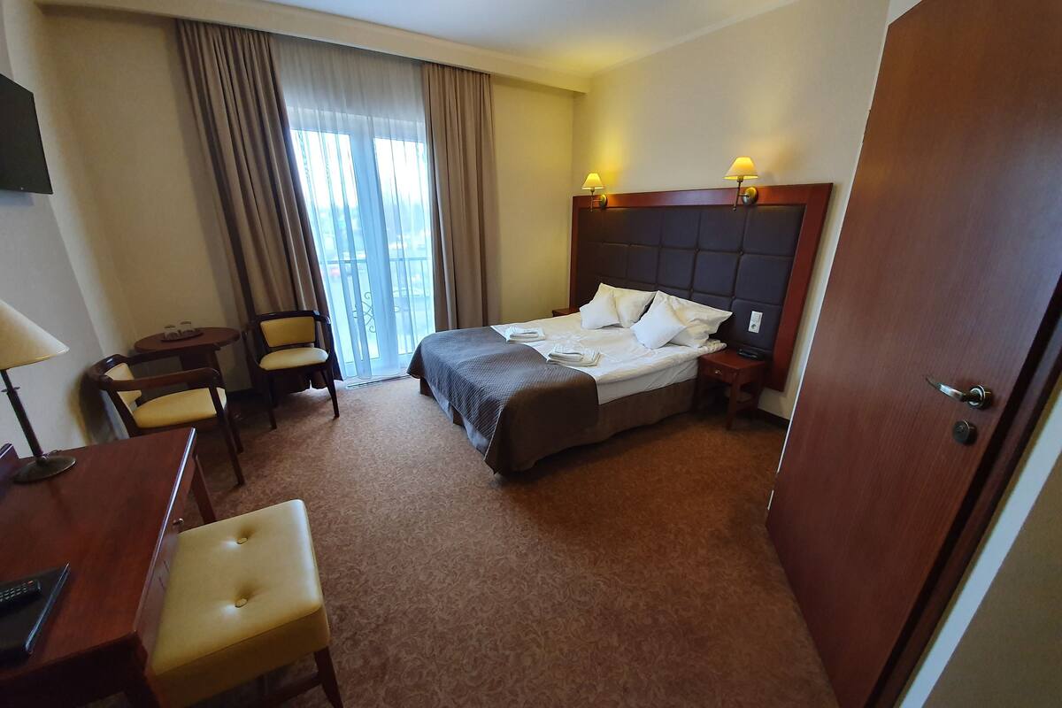 A hotel room with a bed, a desk with a chair, a small table, and a sofa.