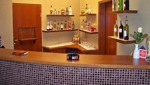 A bar area with shelves of liquor bottles, glasses, and a small plant. - Hotel Gniecki (Pruszcz Gdanski)