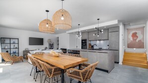 A modern kitchen with a central island, pendant lighting, and a dining area with wicker chairs. - Villa Zen with private 32 sqm pool, summer kitchen, 7 km from the beach (Tugare)