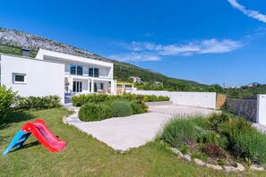 A modern house with a patio, a slide, and a view of a hill. - Villa Zen with private 32 sqm pool, summer kitchen, 7 km from the beach (Tugare)