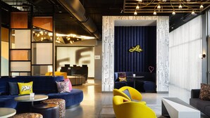 Un espacio lounge moderno con sofás, otomanas y una silla de color amarillo brillante.