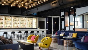 Un área de bar moderna con mostrador, taburetes y asientos que incluyen sofás y sillas.