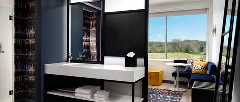A modern bathroom with a large mirror, a white sink, and a towel rack.