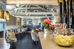 Un restaurant moderne doté d’un bar, de tables et d’éléments décoratifs tels que des fleurs et un bocal rempli de fruits secs.