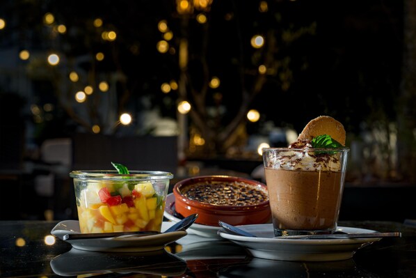 Une table de desserts avec un verre de mousse au chocolat et une salade de fruits.