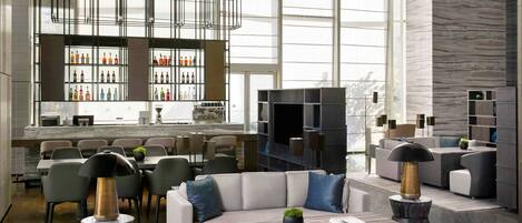 A spacious lobby with a modern bar area, seating arrangements, and large windows providing natural light.