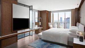 Una habitación de hotel moderna con una cama grande, un televisor de pantalla plana, un escritorio y vistas a la ciudad.